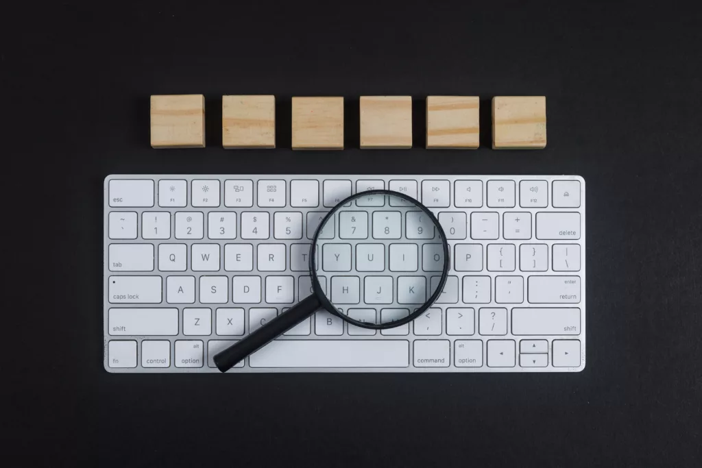 Conceptual of research with keyboard, magnifier, wooden cubes on black desk background flat lay. horizontal image