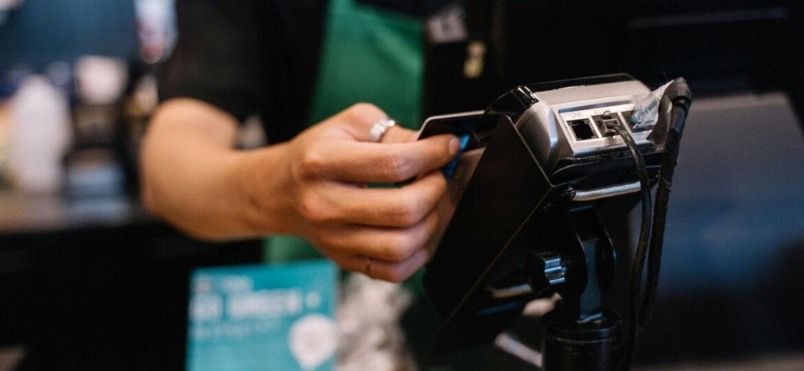 A retail worker handles a transaction in front of a kiosk. (Photo by Anna Tarazevich).