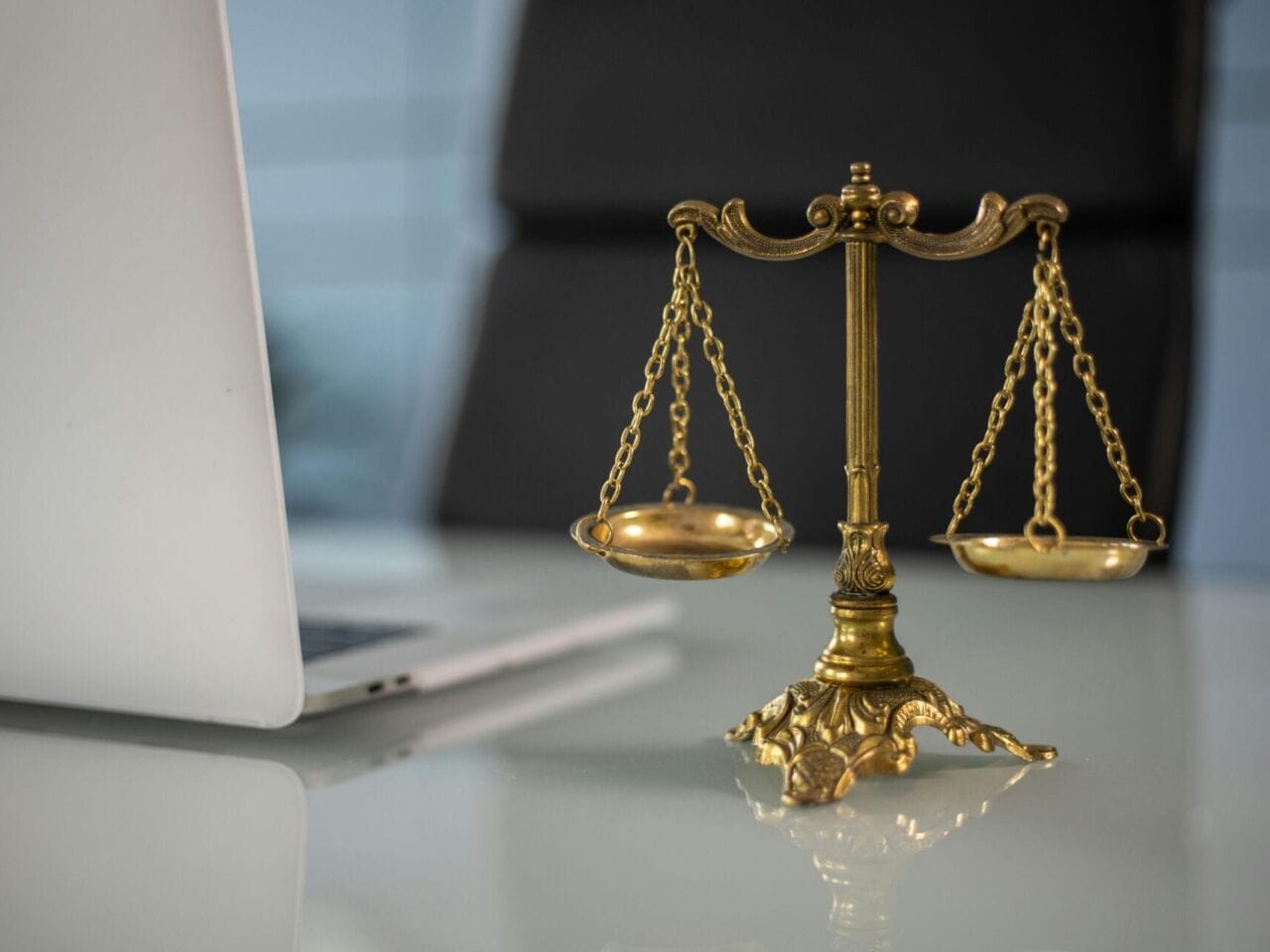 A golden scale to represent justice (Photo by KATRIN BOLOVTSOVA: https://www.pexels.com/photo/a-golden-balance-scale-beside-a-laptop-6077797/).