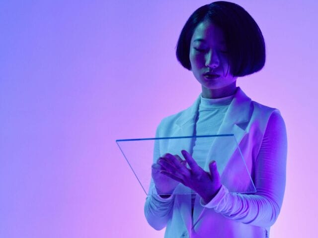 A woman works with a screen technology in a purple-lit room.