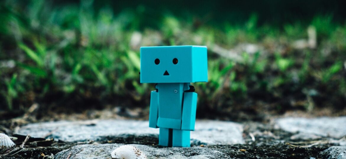 A robot stands on a rock in an outdoor space surrounded by grass. (Photo by: Zamani Sahudi).