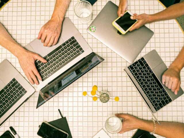 A team displays phones and computers on a meeting table.